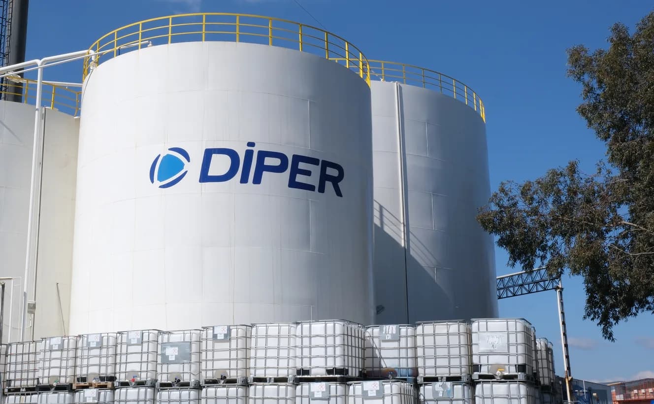 Sarı korkuluklu üç beyaz tank; ortadakinde DİPER logosu, önlerinde istiflenmiş beyaz IBC konteynerler